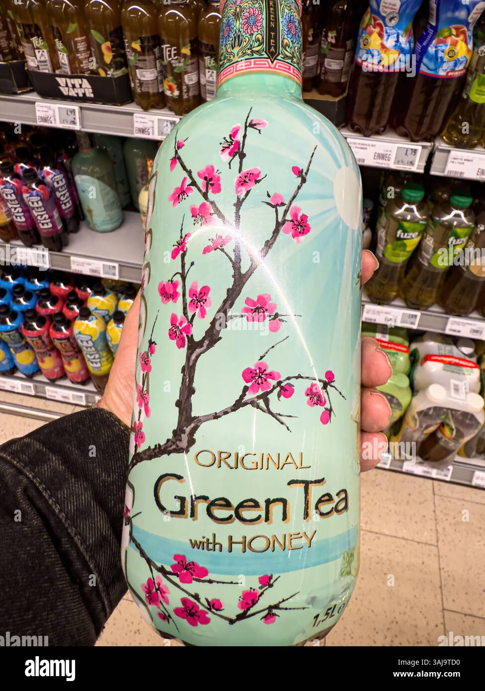 Il cliente sceglie una bottiglia di tè verde dell'arizona con miele in un supermercato, circondato da varie altre bevande - FRANCOFORTE, GERMANIA - 9 APRILE 20 Foto Stock