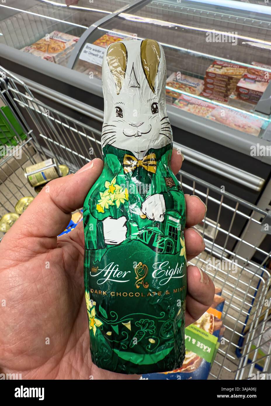 Tenuta a mano dopo otto cioccolatini fondenti e coniglietto pasquale alla menta in un supermercato - FRANCOFORTE, GERMANIA - 9 APRILE 2025 Foto Stock