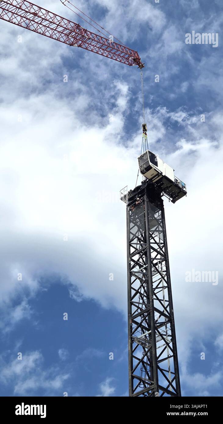 Posizionamento della gru a torre; la torre e la cabina sono all'interno e il braccio è stato aggiunto Foto Stock