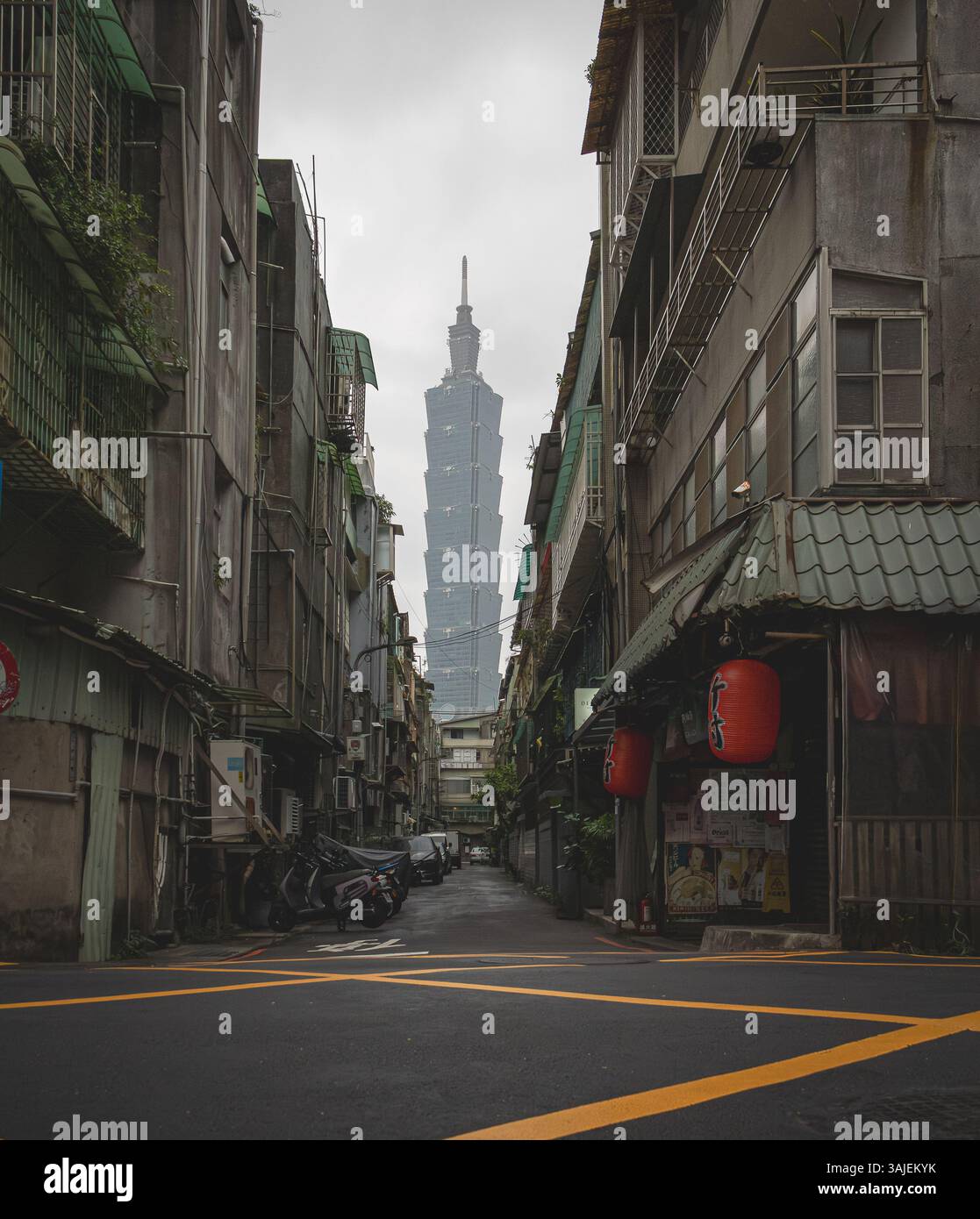 Persona con in mano un ombrello viola e un edificio Taipei 101 sullo sfondo di una strada cittadina a Taiwan. Foto scattata su una nuvolosa in una giornata nuvolosa Foto Stock