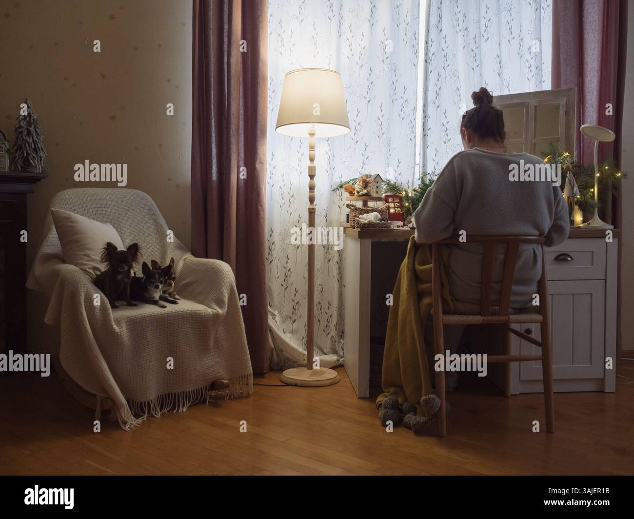 Vista posteriore di una donna che lavora nella sua accogliente sala festiva con cani Foto Stock