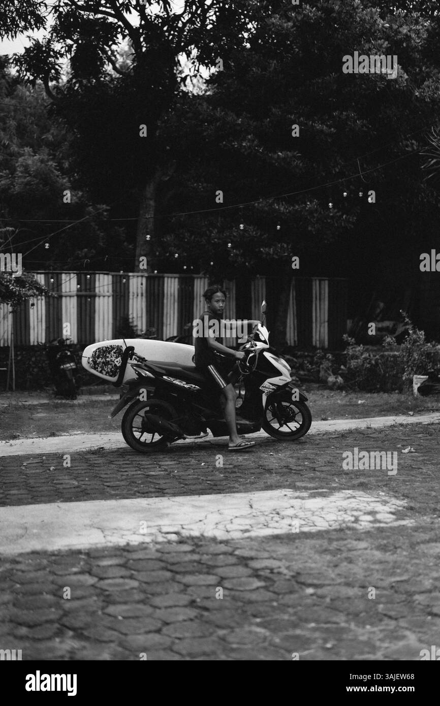 Un ragazzo indonesiano va in bicicletta per fare surf Foto Stock