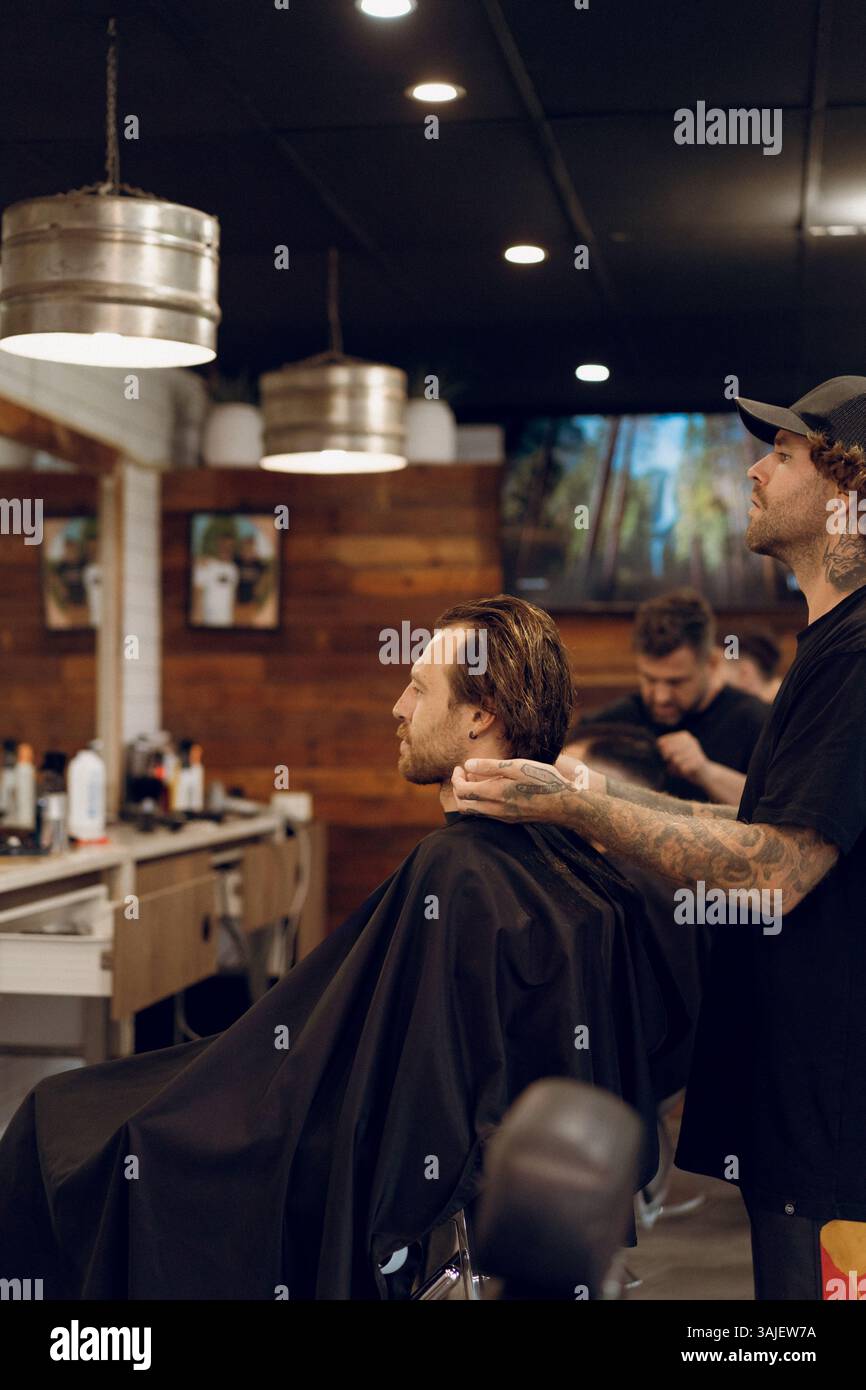 Taglio del barbiere giovane di capelli in salone Foto Stock