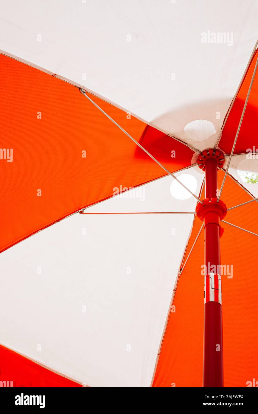 Ombrello esterno arancione luminoso che fornisce ombra in una giornata di sole Foto Stock