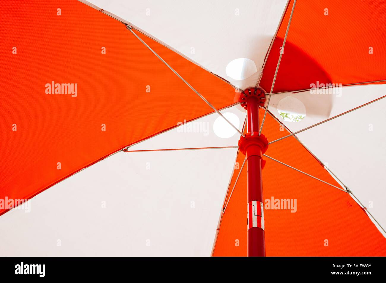 L'ombrello arancione luminoso offre ombra nelle giornate di sole all'aperto Foto Stock