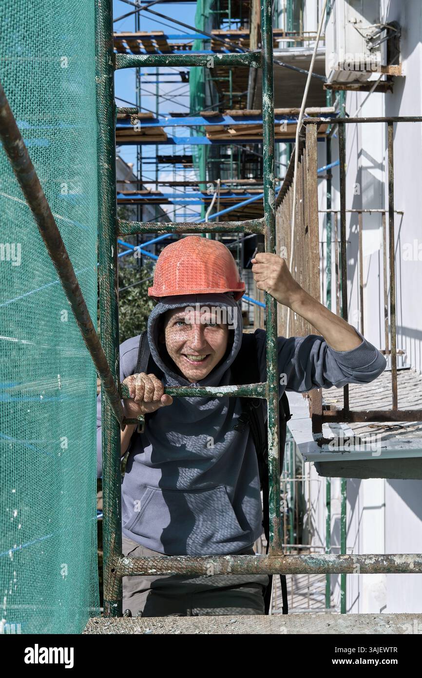 Operaio edile che arrampica ponteggi in un cantiere Foto Stock