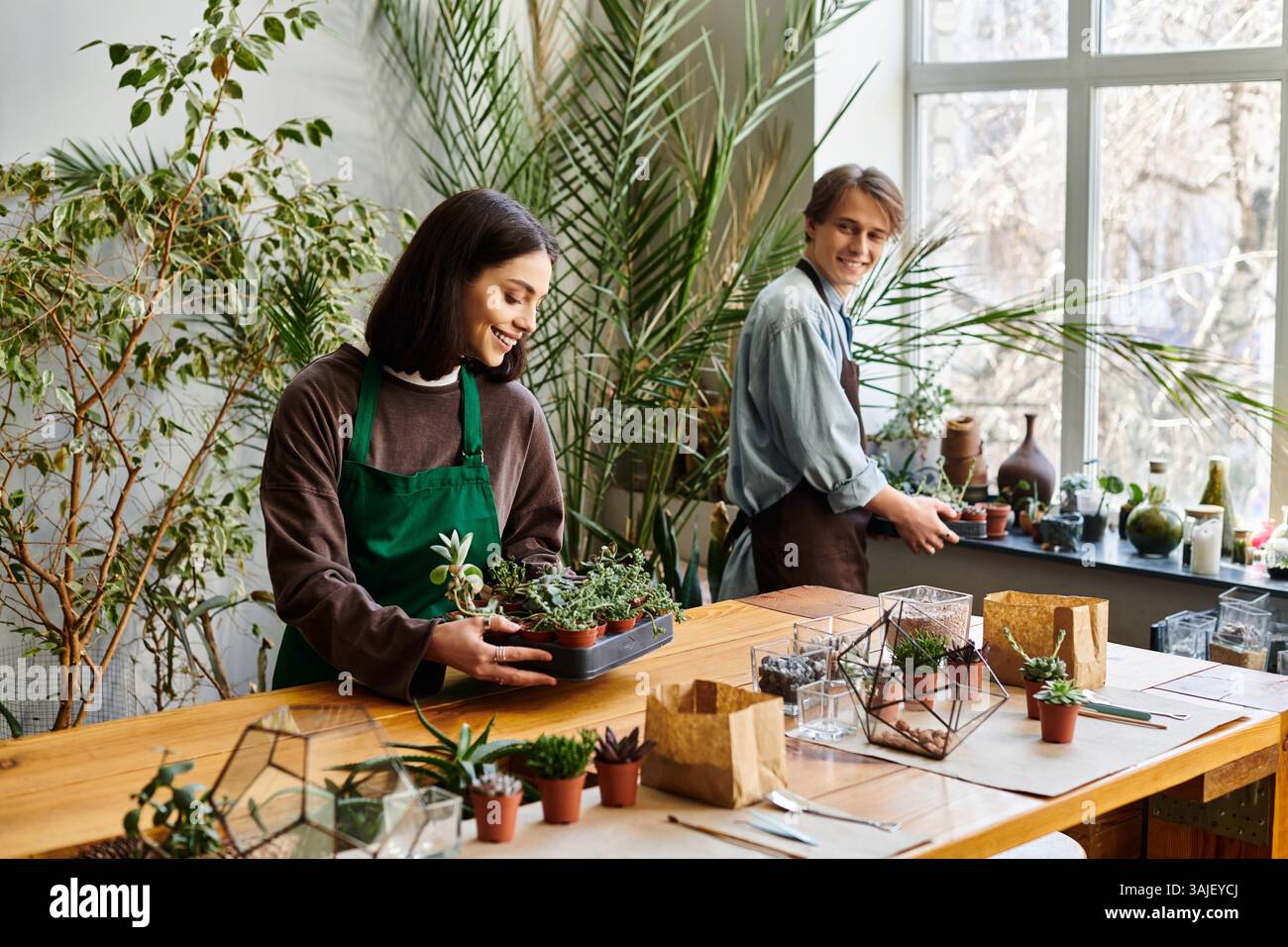 Una coppia amorevole crea arte tra piante, strumenti e luce solare. Foto Stock
