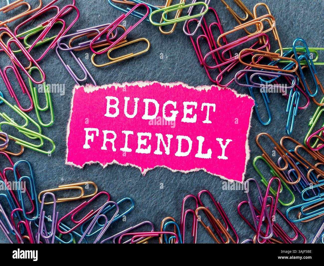 Messaggio economico scritto su un pezzo di carta rosa strappato su sfondo grigio. Simbolo di budget concettuale. Copia spazio. Foto Stock