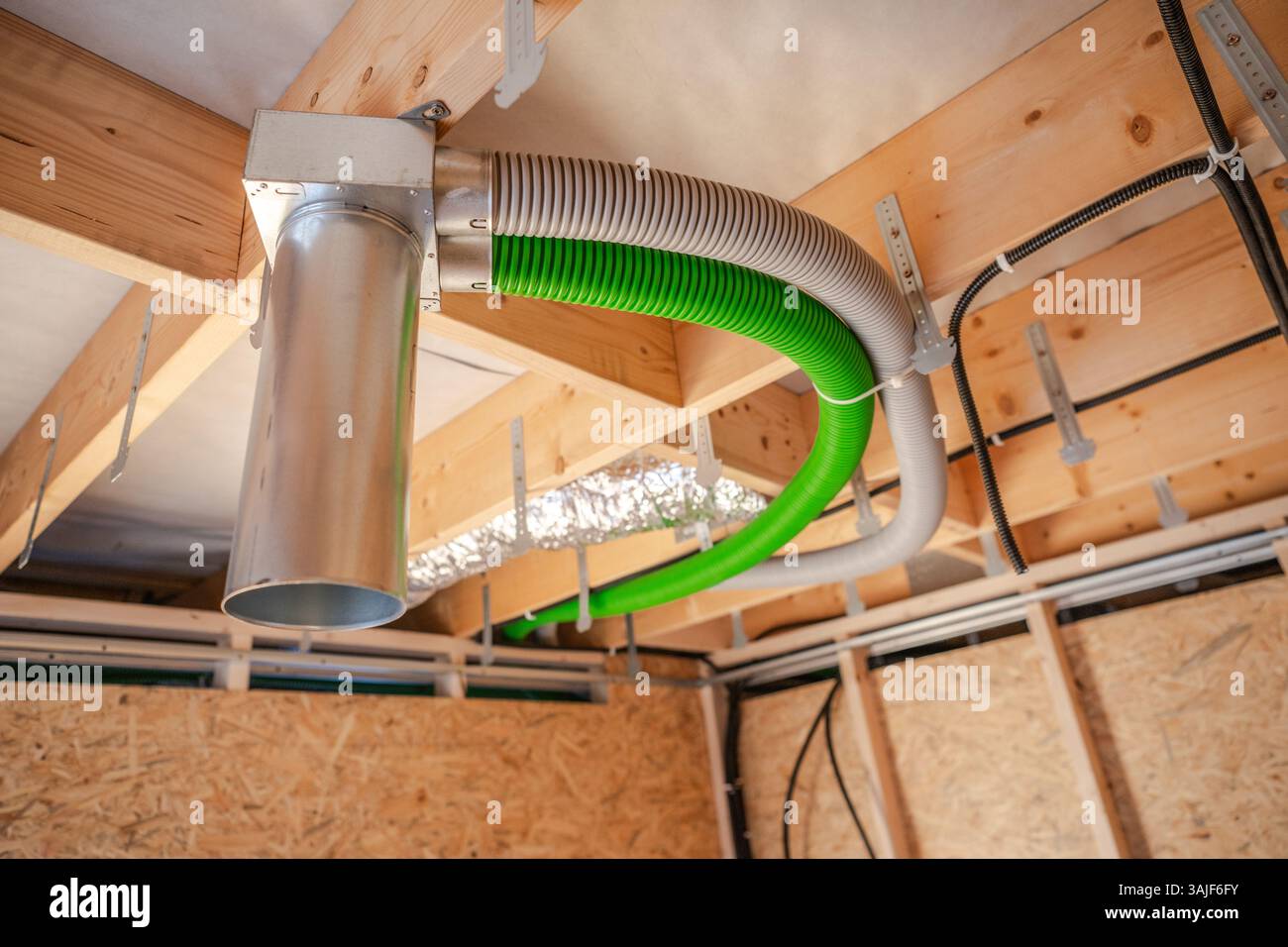 È in corso l'installazione di un sistema di ventilazione in una casa di nuova costruzione. L'immagine mostra condotti colorati attaccati ai fasci del soffitto, a indicare la progr Foto Stock
