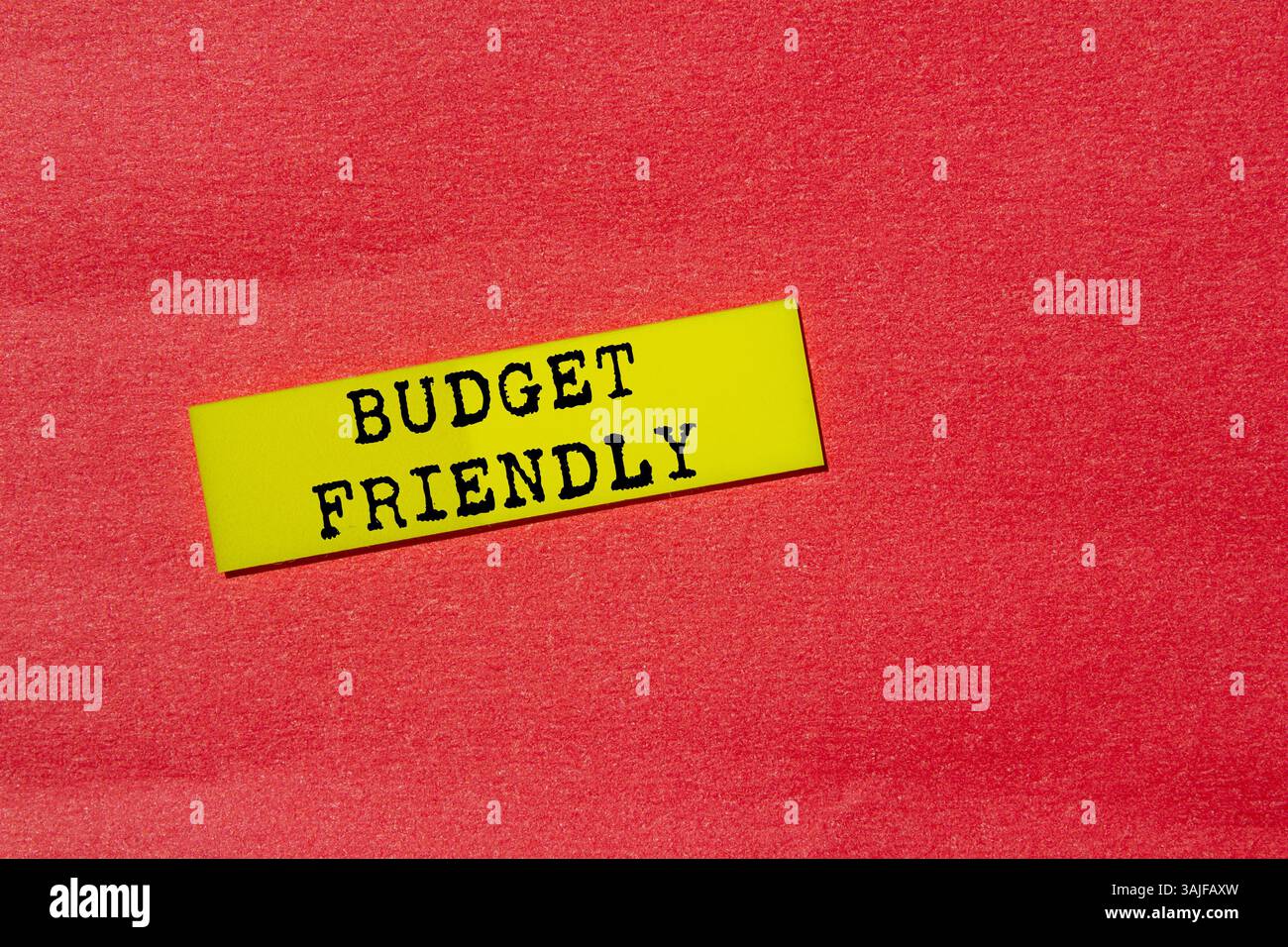 Messaggio economico scritto su etichetta di carta gialla su sfondo rosso. Simbolo di budget concettuale. Copia spazio. Foto Stock