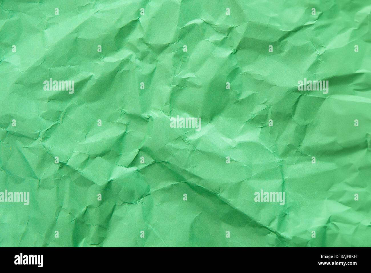 Un primo piano dall'alto verso il basso mette in mostra la trama increspata e irregolare della carta verde. Concetto di background. Foto Stock
