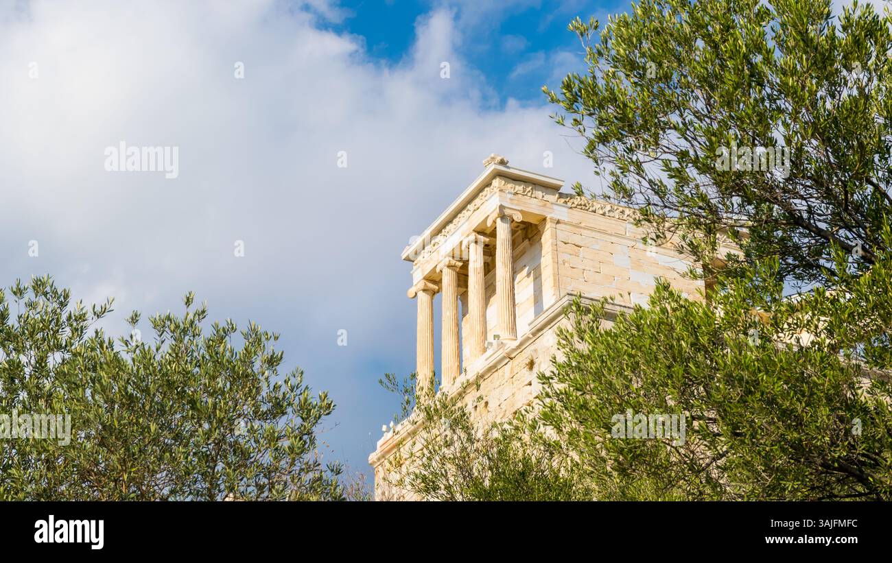 Il Tempio bianco di Atena Nike sull'Acropoli della collina di Atene attraverso gli ulivi verdi, in Grecia Foto Stock