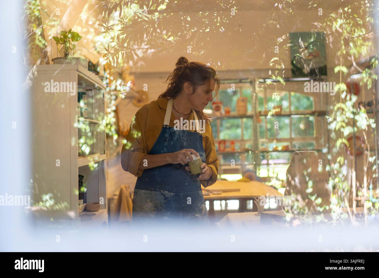 L'artista ha visto lavorare dietro una finestra nel suo studio di ceramica Foto Stock