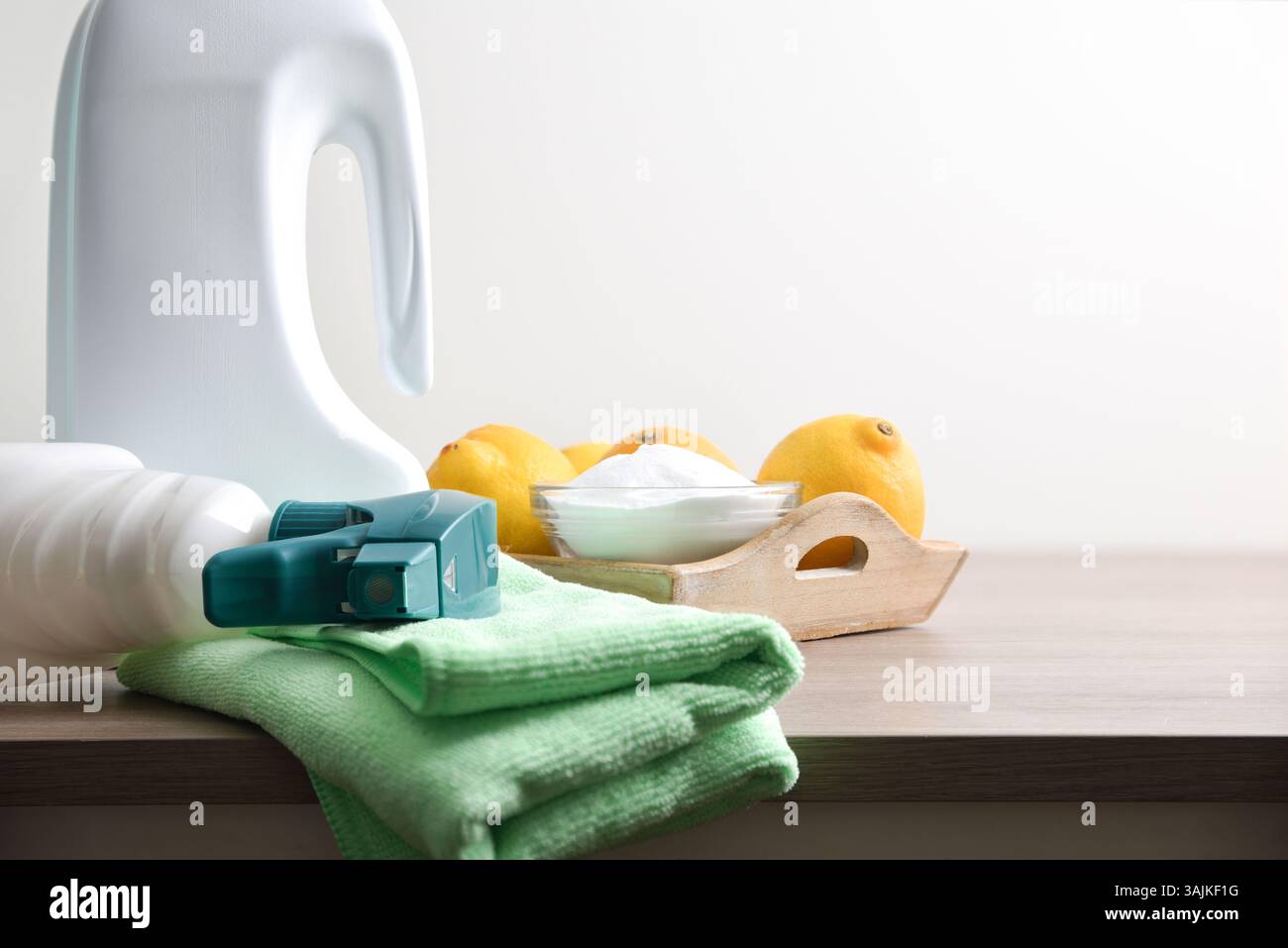 Diversi tipi di prodotti per la pulizia, sia chimici che naturali, su un tavolo in legno con bottiglie di prodotti disinfettanti, stracci, spazzole, limoni e bo Foto Stock