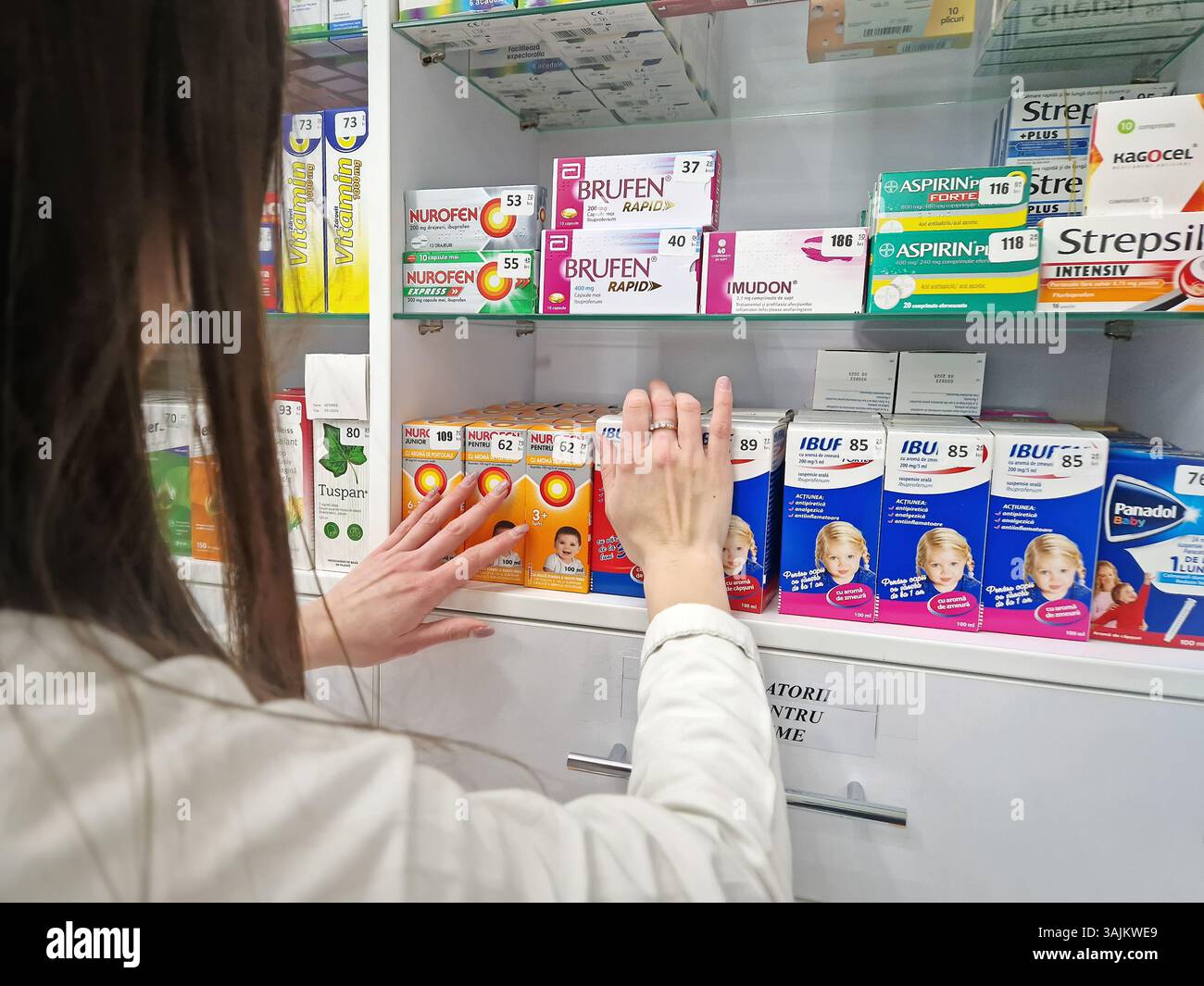 UNGHENI, MOLDAVIA - 15 GENNAIO 2024 Vista ravvicinata con i negozi di farmacista donna e organizza medicine sugli scaffali all'interno della farmacia. Assistenza sanitaria e - Immagine stock catturata con smartphone