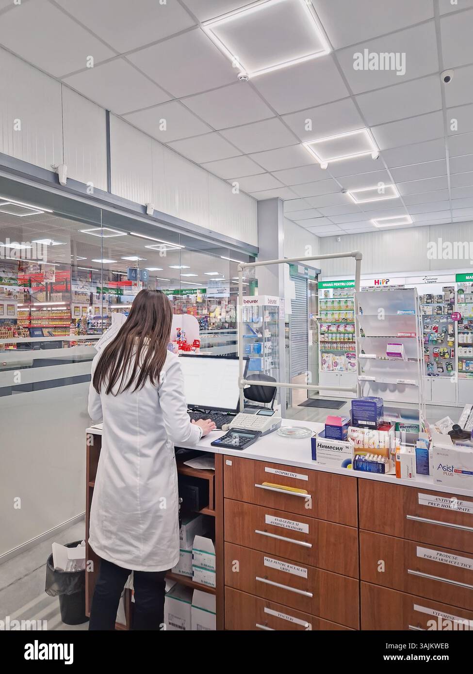 UNGHENI, MOLDAVIA - 20 GENNAIO 2024 vista all'interno della farmacia con una donna farmacista che lavora al banco di vendita di fronte al computer. Medi farmacia - Immagine stock catturata con smartphone