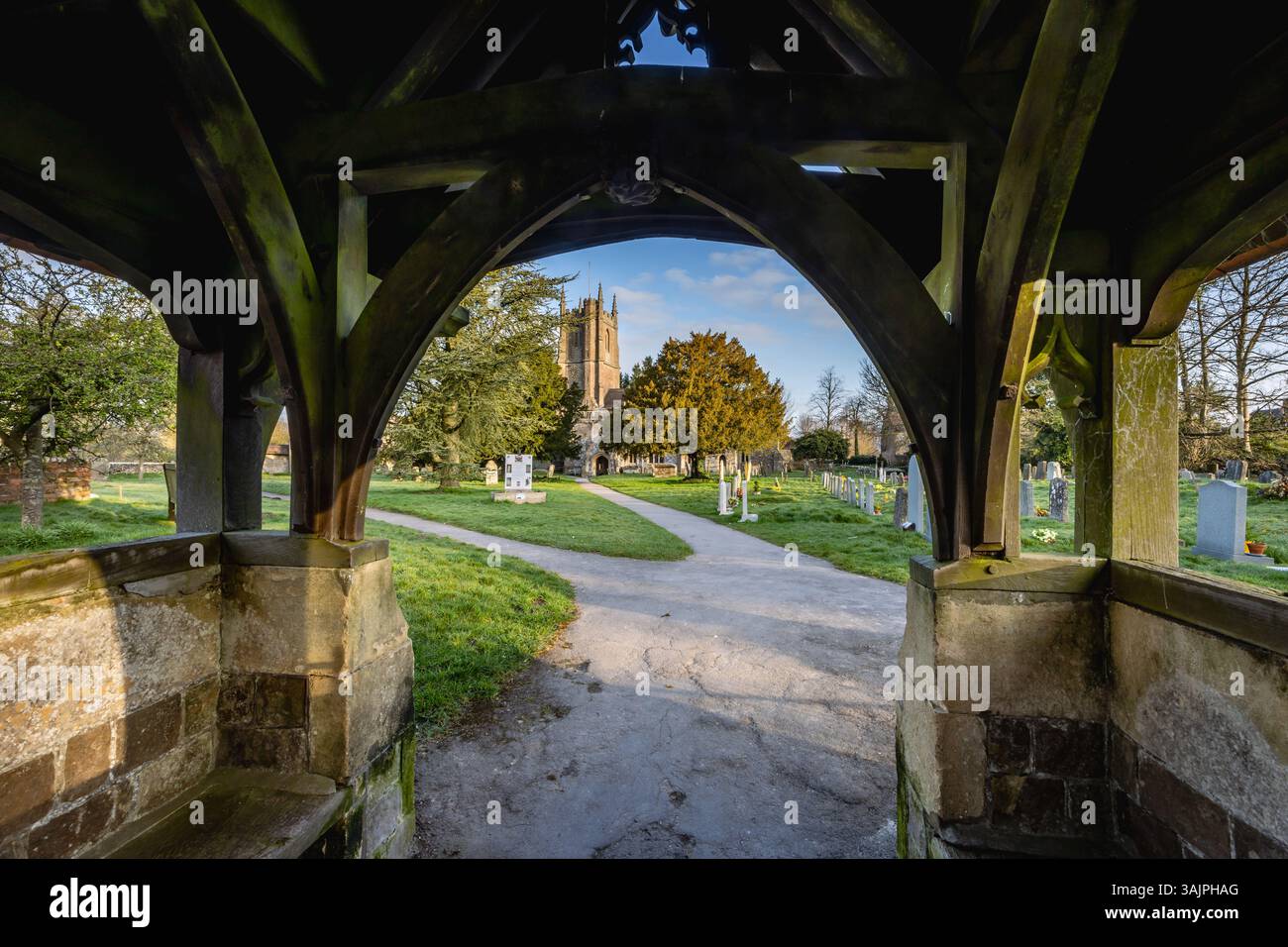 Vista attraverso il cancello del grazioso cimitero e la chiesa di St James ad Avebury, Wiltshire Foto Stock