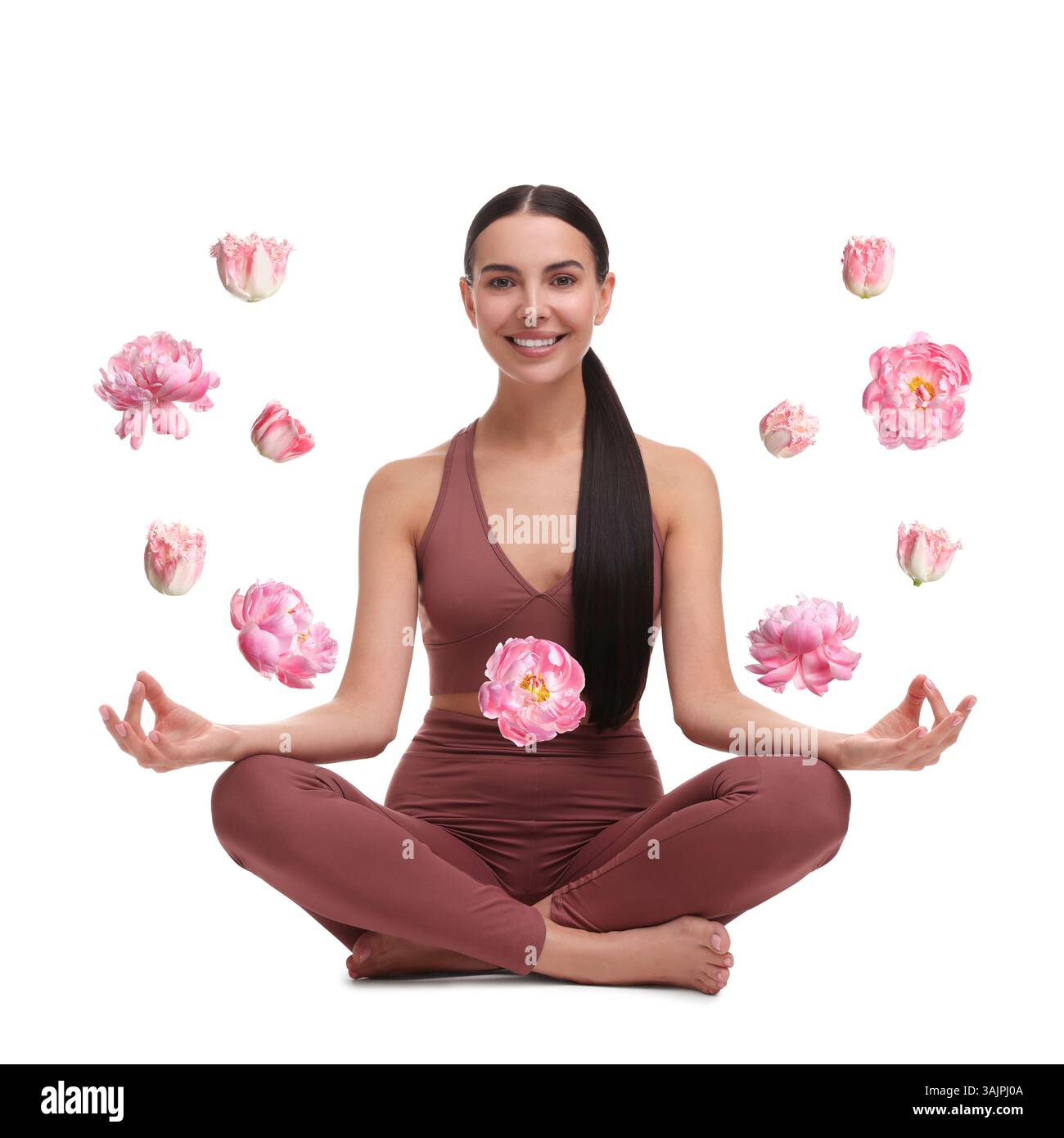 Bella giovane donna che pratica yoga circondata da fiori volanti su sfondo bianco Foto Stock