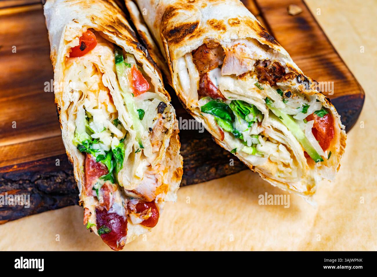 Un gustoso involtino è ripieno di pollo alla griglia, lattuga croccante, pomodori a dadini e formaggio grattugiato. L'involucro tostato presenta un pasto appetitoso, perf Foto Stock