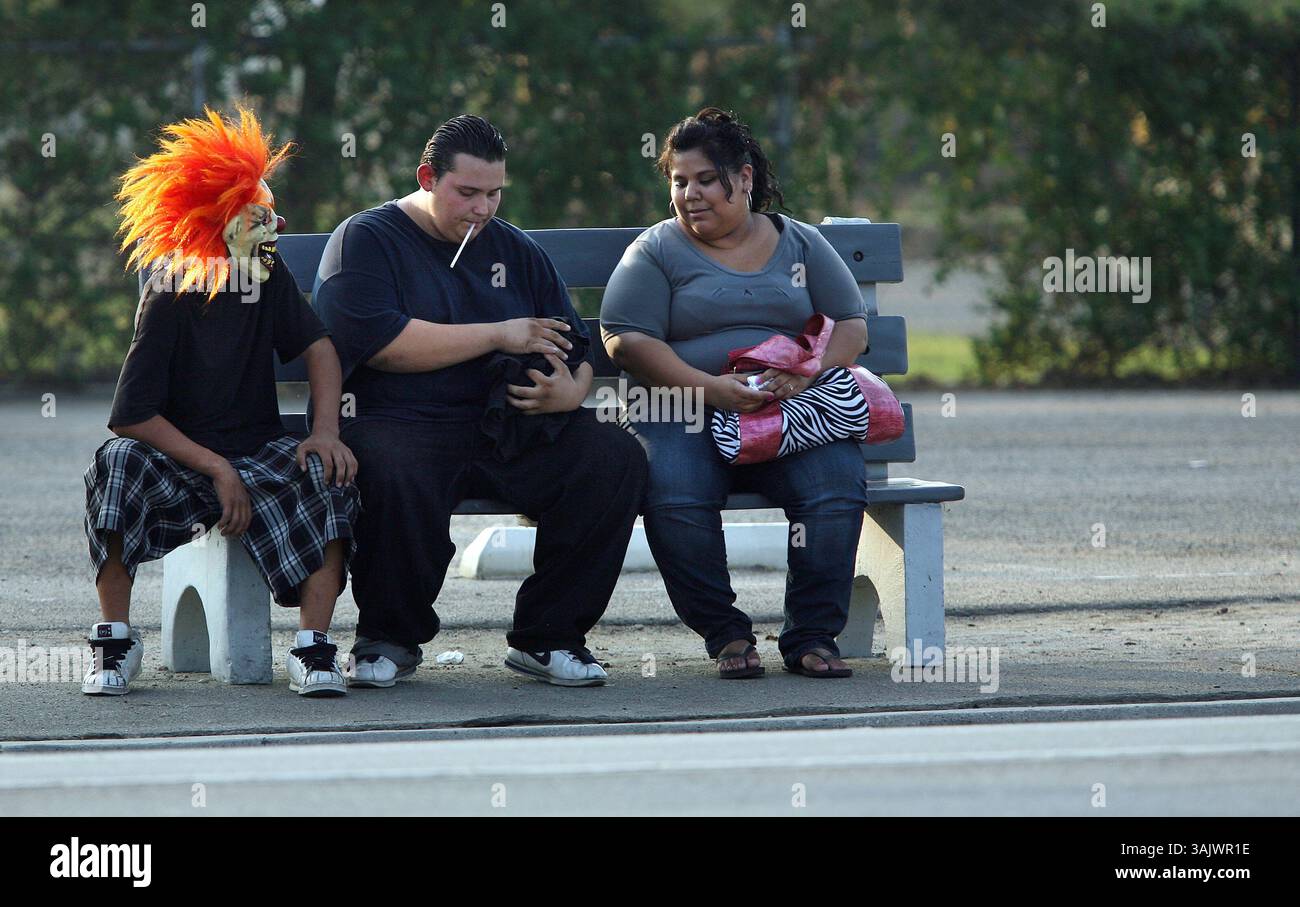 Casey Christie / The Californian. Tre amici aspettano l'autobus cittadino, sabato, su Chester Avenue, alla 34th Street. Uno a sinistra è un po' presto per Halloween, con indosso una maschera umoristica. (Immagine di credito: © The Bakersfield Californian/ZUMA Press) Foto Stock