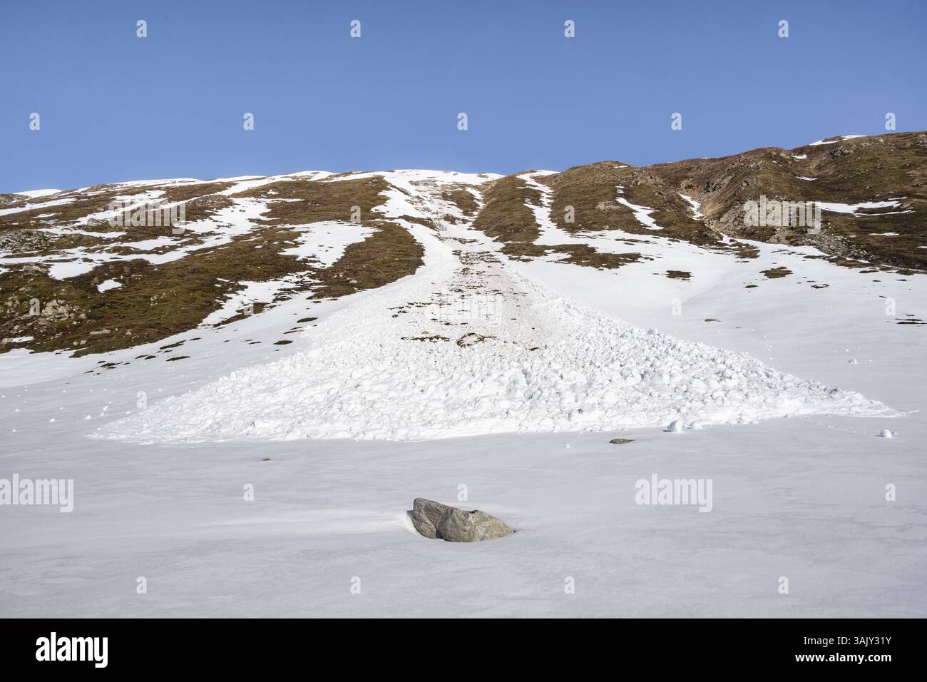 Valanga di neve su un ripido pendio erboso, situazione primaverile, Graubuenden, Svizzera, Europa Foto Stock