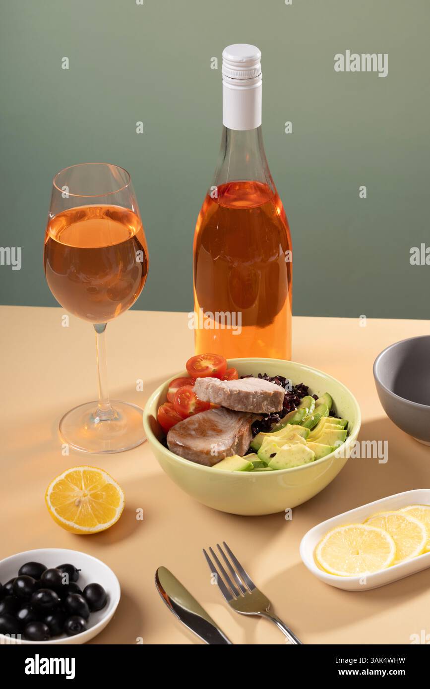 Una ciotola di gustosa insalata di tonno e verdure, un bicchiere di vino, un moderno naturismo su una tavola colorata, piano piatto. Posiziona per testo. Foto di alta qualità Foto Stock