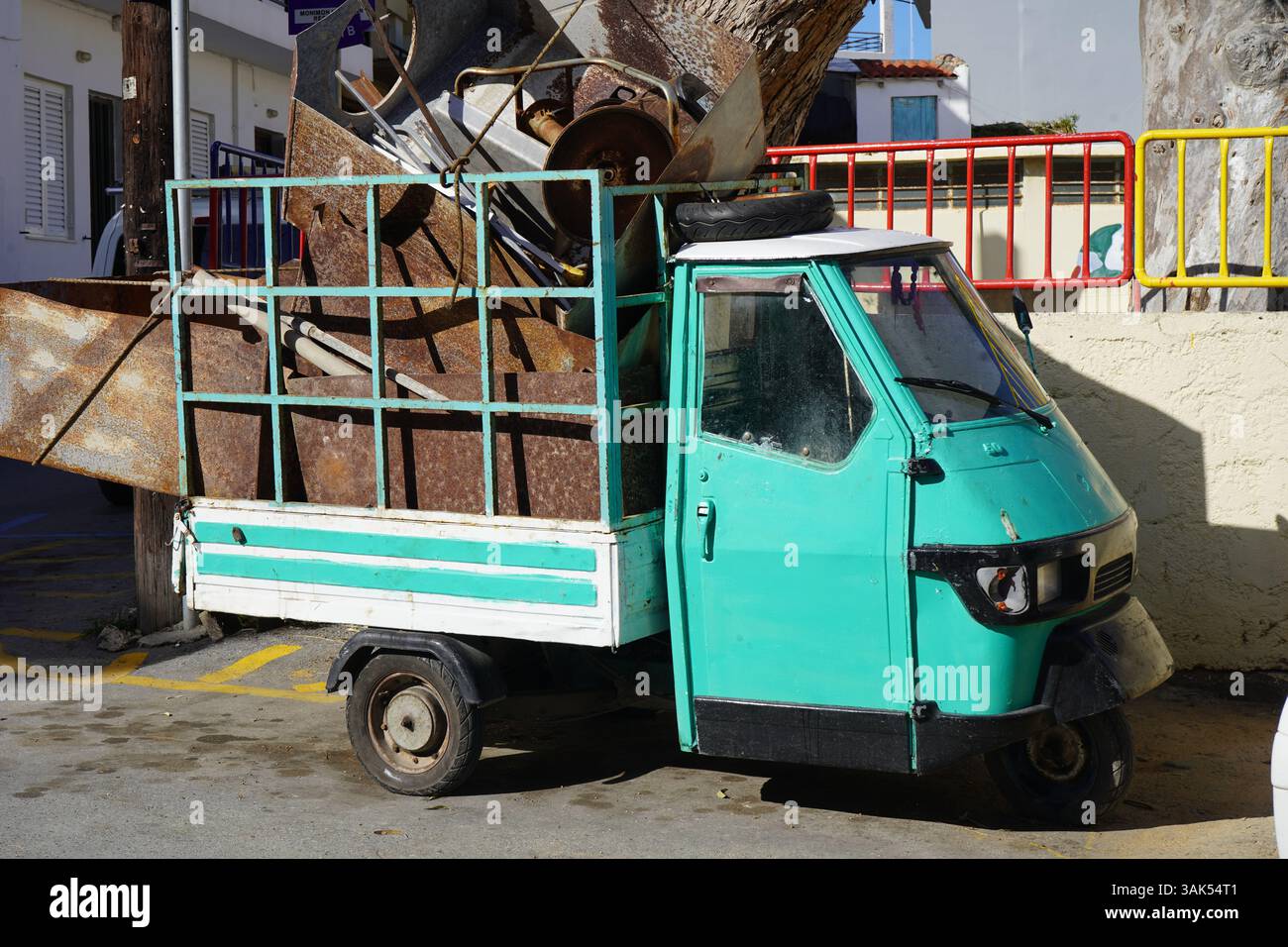 Moto d'epoca (triciclo per adulti) in un bellissimo colore verde caricato con rottami metallici - moto retro per il trasporto merci. Vintag Foto Stock
