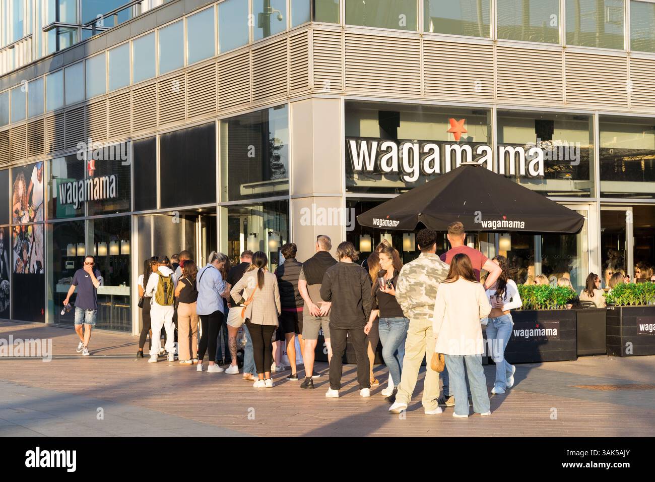 Una lunga fila di ristoranti visti fuori dal ristorante Wagamama, in una serata primaverile molto soleggiata, Londra Regno Unito Foto Stock