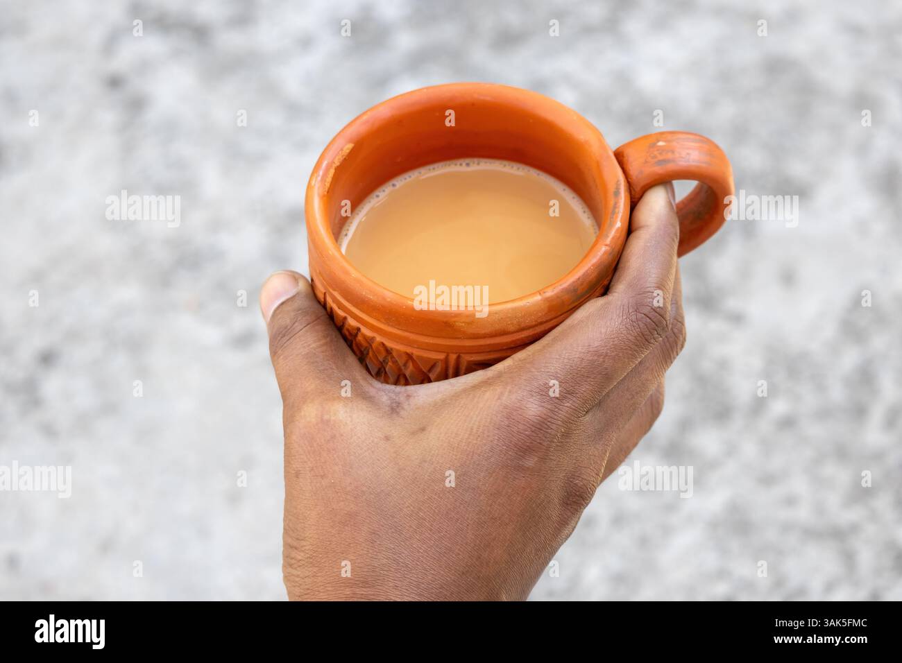 Una mano femminile tiene il tè caldo al latte, noto anche come dudh cha o Kullad chai, in una tradizionale tazza di argilla. Foto Stock