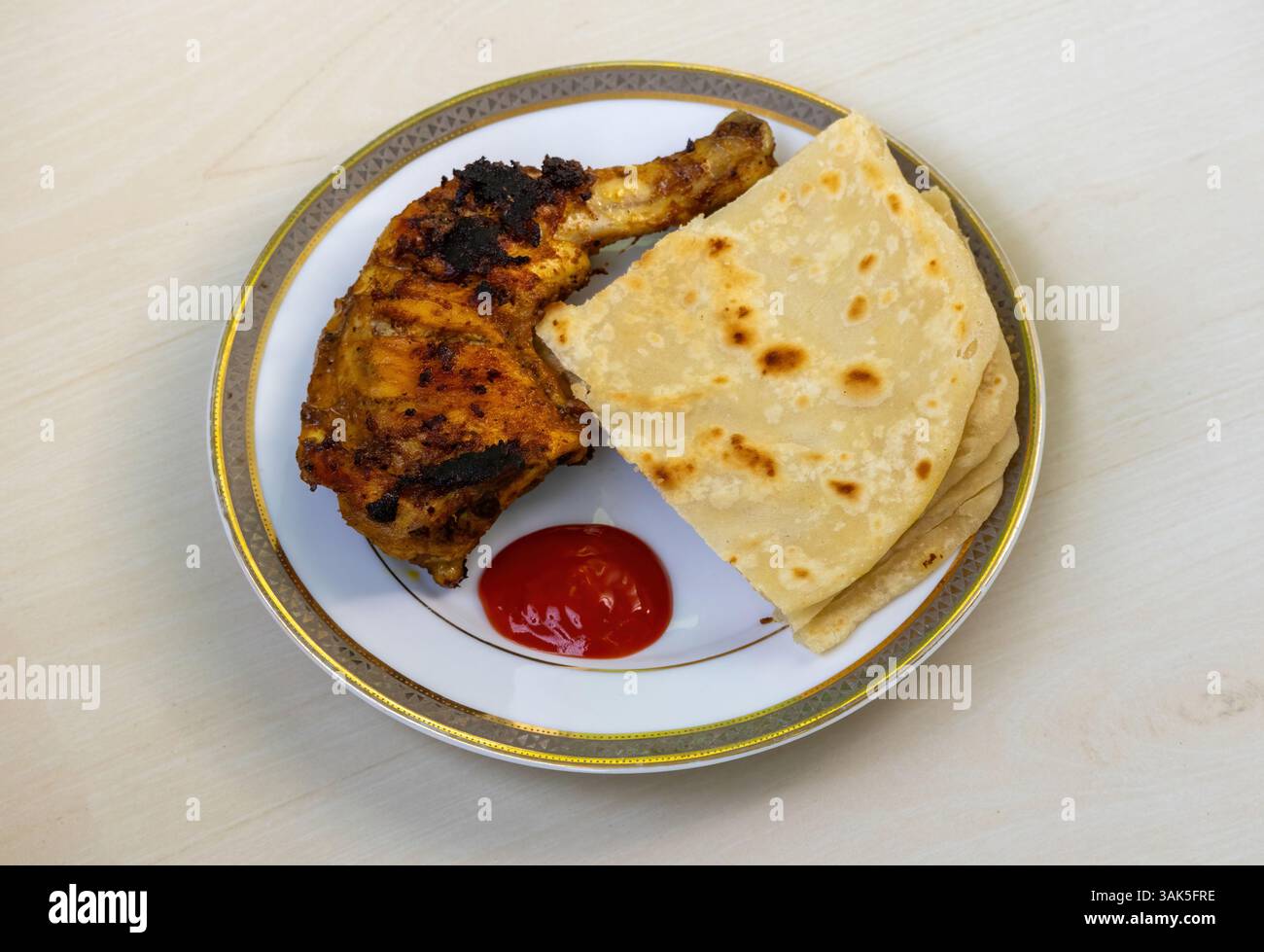 Delizioso pollo alla griglia fatto in casa con pezzi tagliati di Paratha e salsa di pomodoro servito su un piatto di ceramica. Un gustoso tostato in stile bengalese Foto Stock