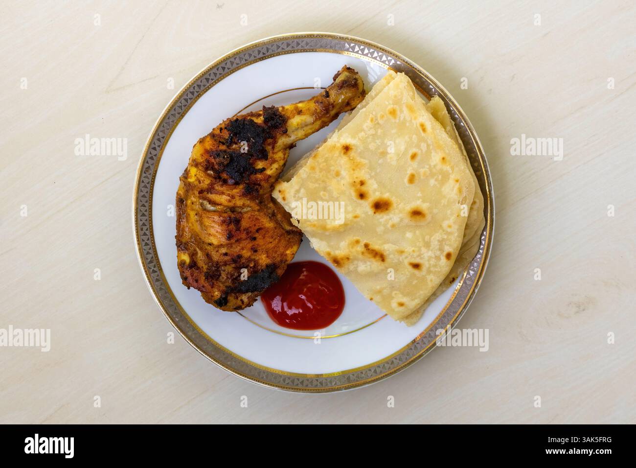 Delizioso pollo alla griglia fatto in casa, servito con pezzi tagliati di Paratha e salsa di pomodoro su un piatto di ceramica. Un Bengala molto gustoso e nutriente Foto Stock