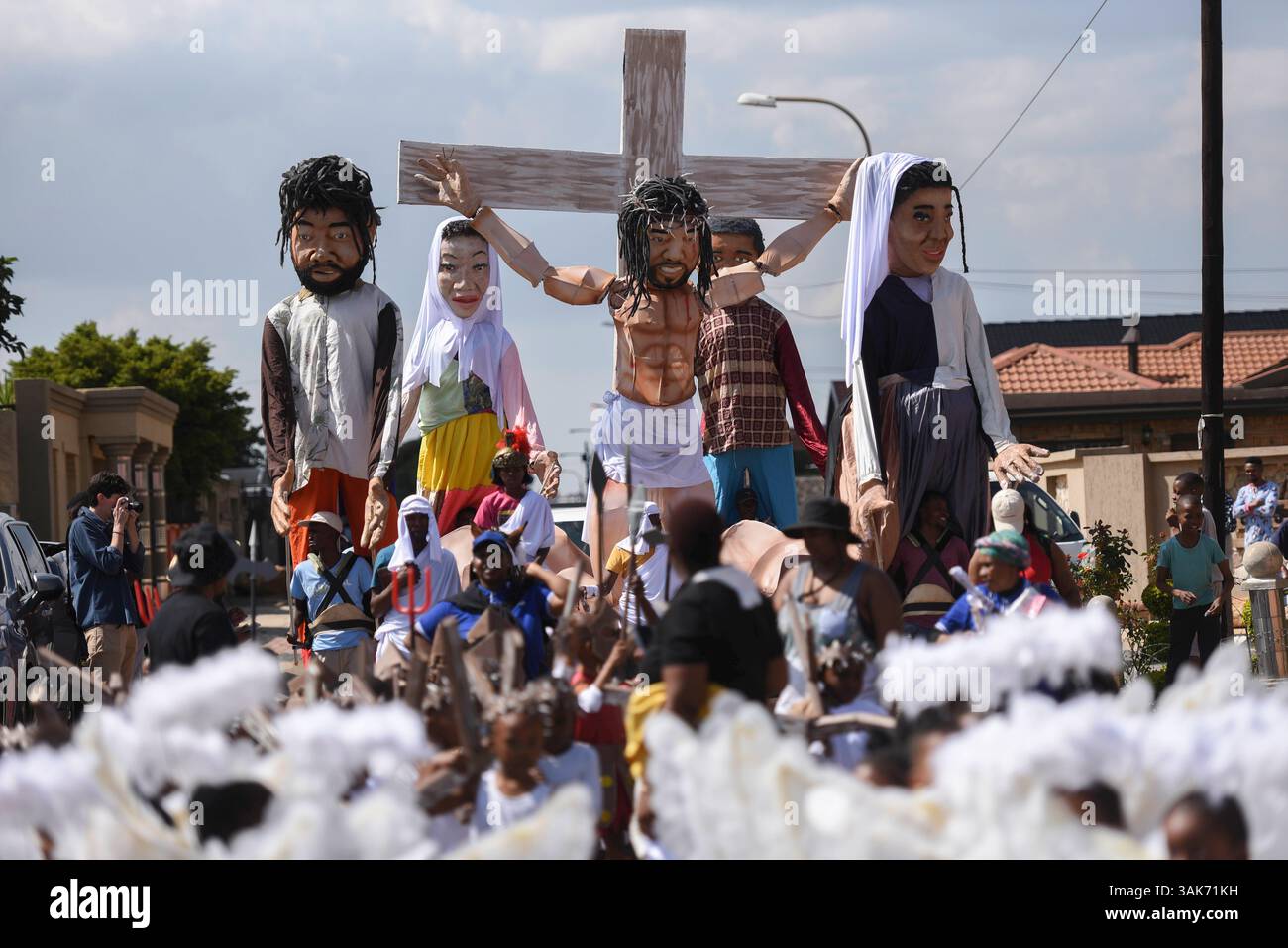 The Passion of the Christ Production in Sud Africa i partecipanti partecipano alla Passion of the Christ Parade, una collaborazione tra la scuola ECD per lo sviluppo della prima infanzia Kiddies Hope Academy e la Nkosana Ngobese Foundation attraverso le strade di Dobsonville, Soweto, Sud Africa 12 aprile 2025. La passione della produzione di Cristo è una rappresentazione drammatica dell'ultimo giorno della vita di Gesù, culminante nella crocifissione. La produzione presentava bambini di 5 e 6 anni in costumi, vestiti da angeli, Gesù che trasportava una croce e soldati romani, oltre a marionette giganti che interpretavano il ruolo di Jesu Foto Stock