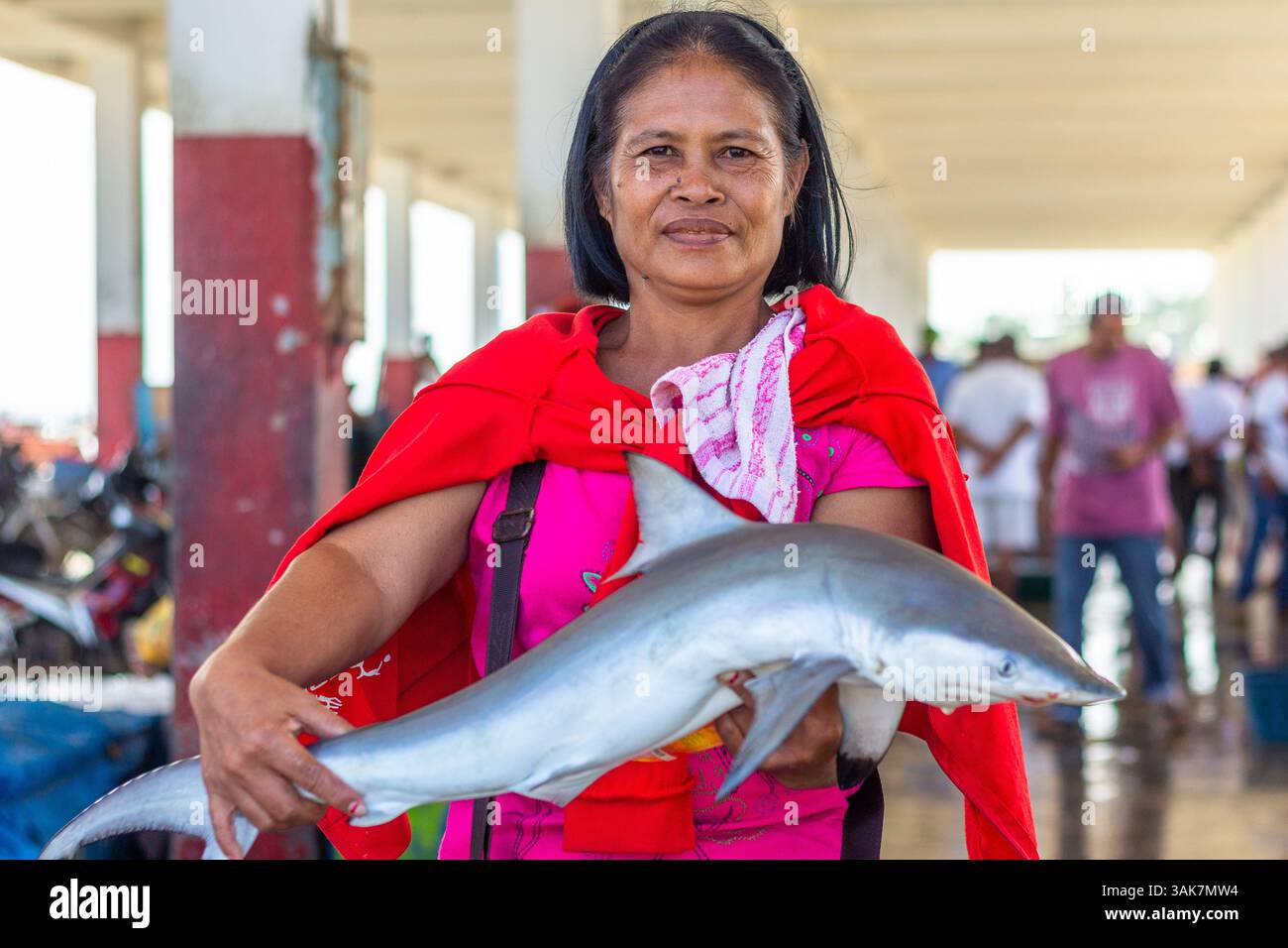 Un venditore di mezza età del mercato filippino detiene un piccolo squalo in un mercato locale a Iloilo, nelle Filippine Foto Stock