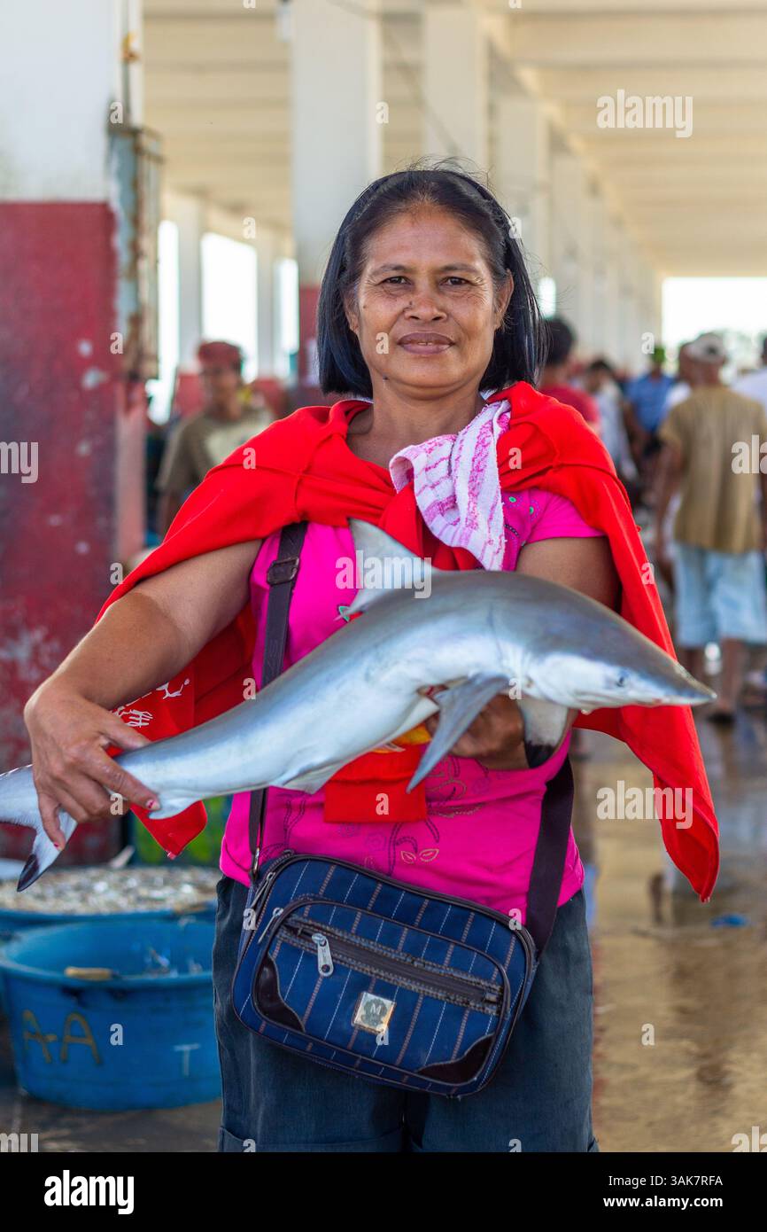 Un venditore di mezza età del mercato filippino detiene un piccolo squalo in un mercato locale a Iloilo, nelle Filippine Foto Stock