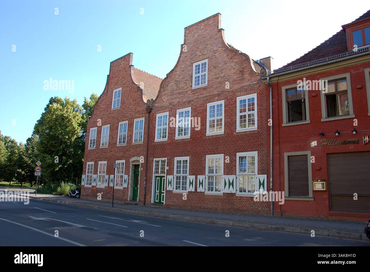 Tradizionali case in mattoni rossi nel quartiere olandese (Holländisches Viertel) di Potsdam, Germania, che costeggiano una strada acciottolata con auto parcheggiate in una giornata di sole Foto Stock