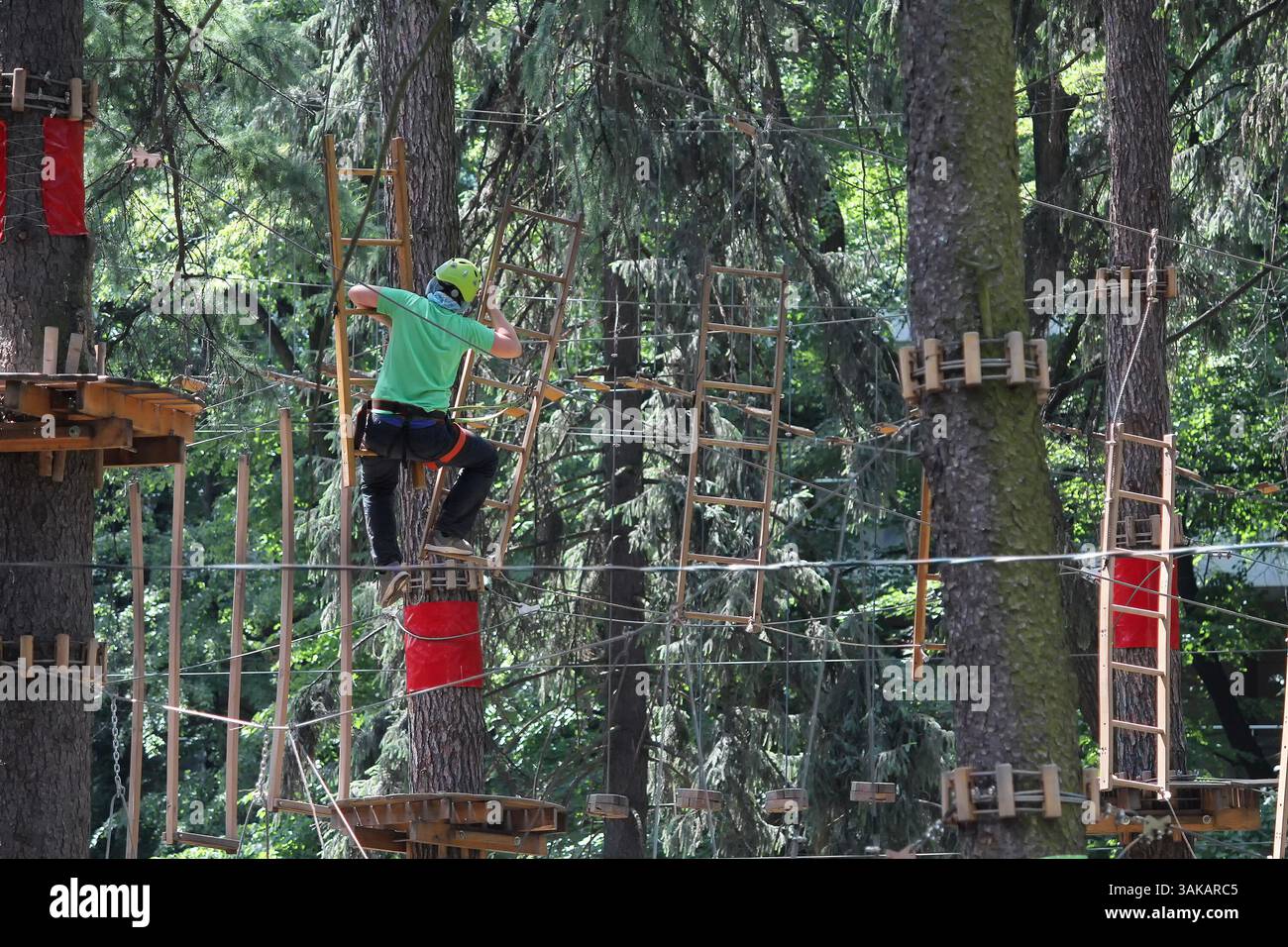 Persone in un parco di corda per casco in vacanza attiva nella foresta. Vacanza estrema Foto Stock