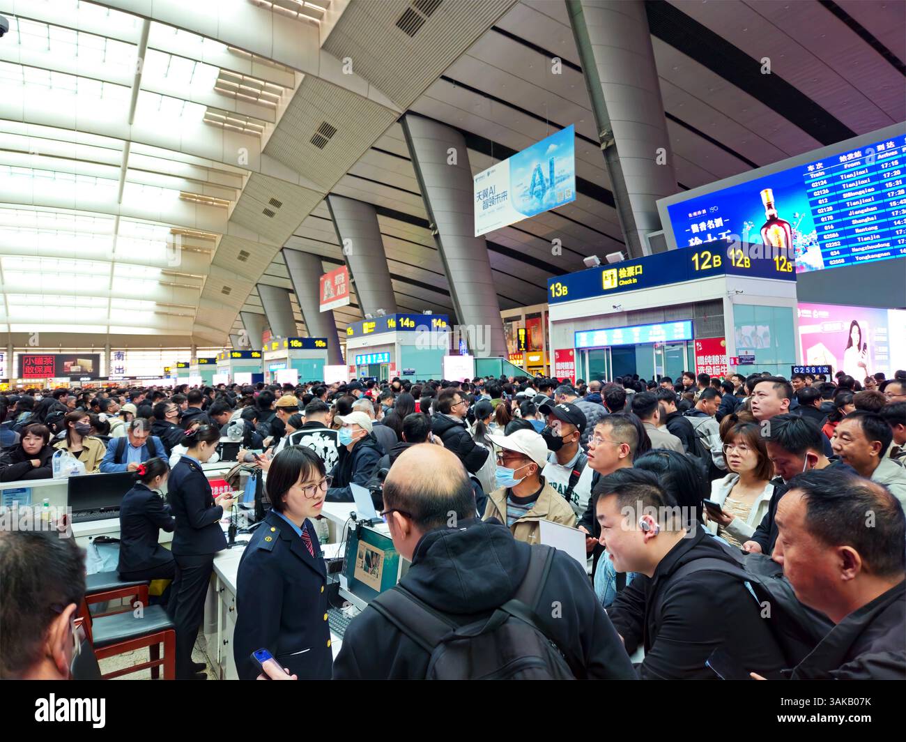 Pechino, Cina, 12 aprile 2025 — il personale sopraffatto assiste i passeggeri bloccati alla stazione ferroviaria sud di Pechino quando i forti venti causano ritardi e cancellazioni diffusi nei servizi ferroviari ad alta velocità, interrompendo i trasporti pubblici in tutta la Cina settentrionale Foto Stock