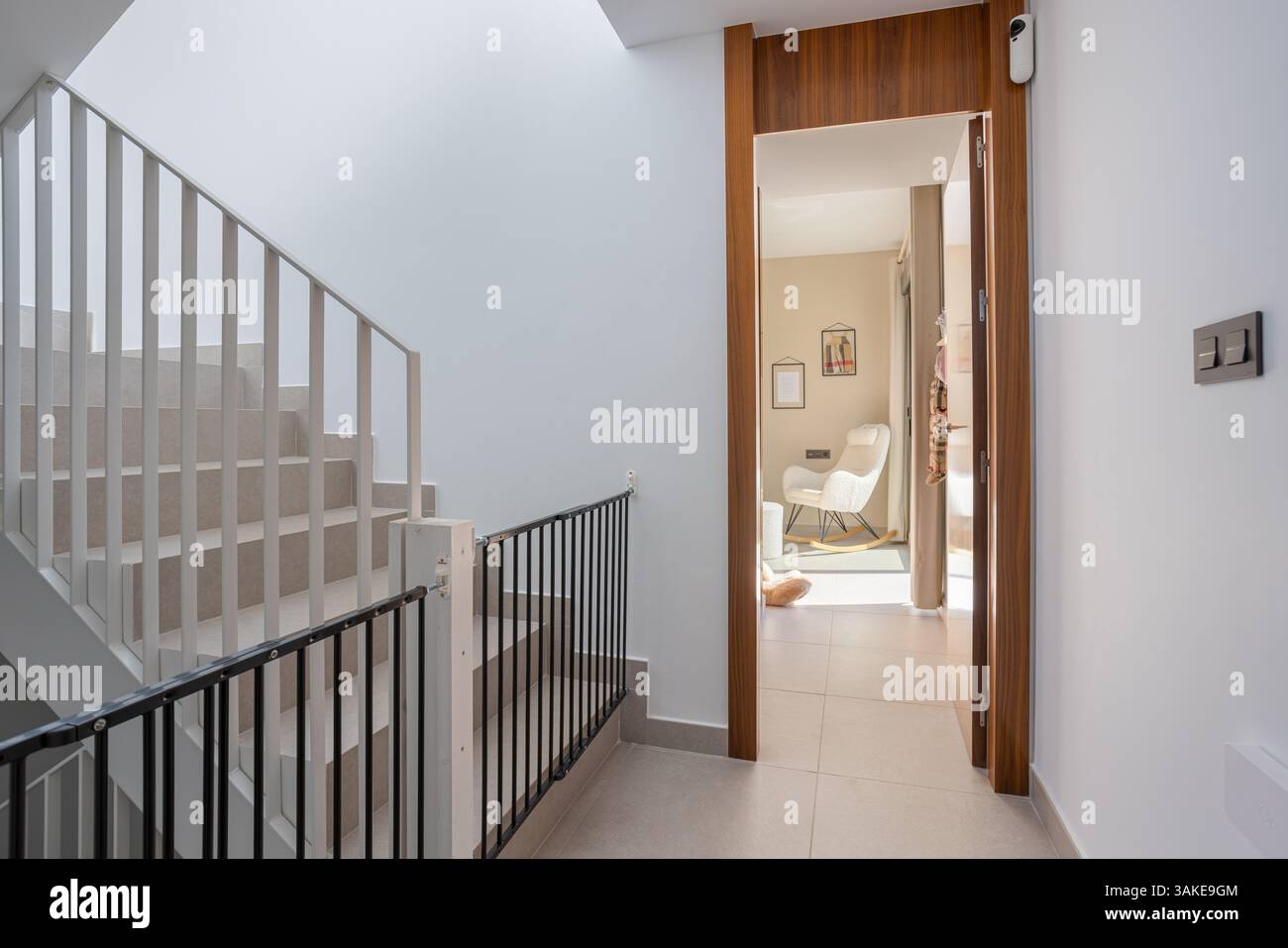 Scala pulita e moderna con cancello di sicurezza per bambini, che conduce ad una camera accogliente e ben illuminata in una casa contemporanea. Foto Stock