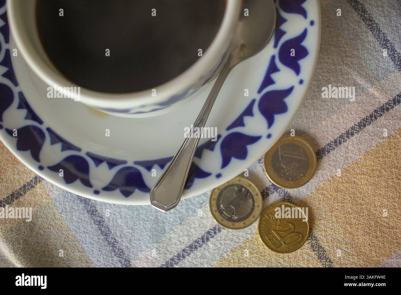 tazza da caffè nera e monete sul tavolo Foto Stock