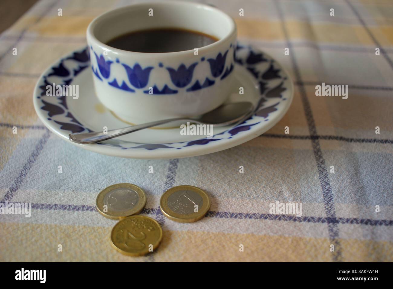 monete e un caffè nero sul tavolo Foto Stock