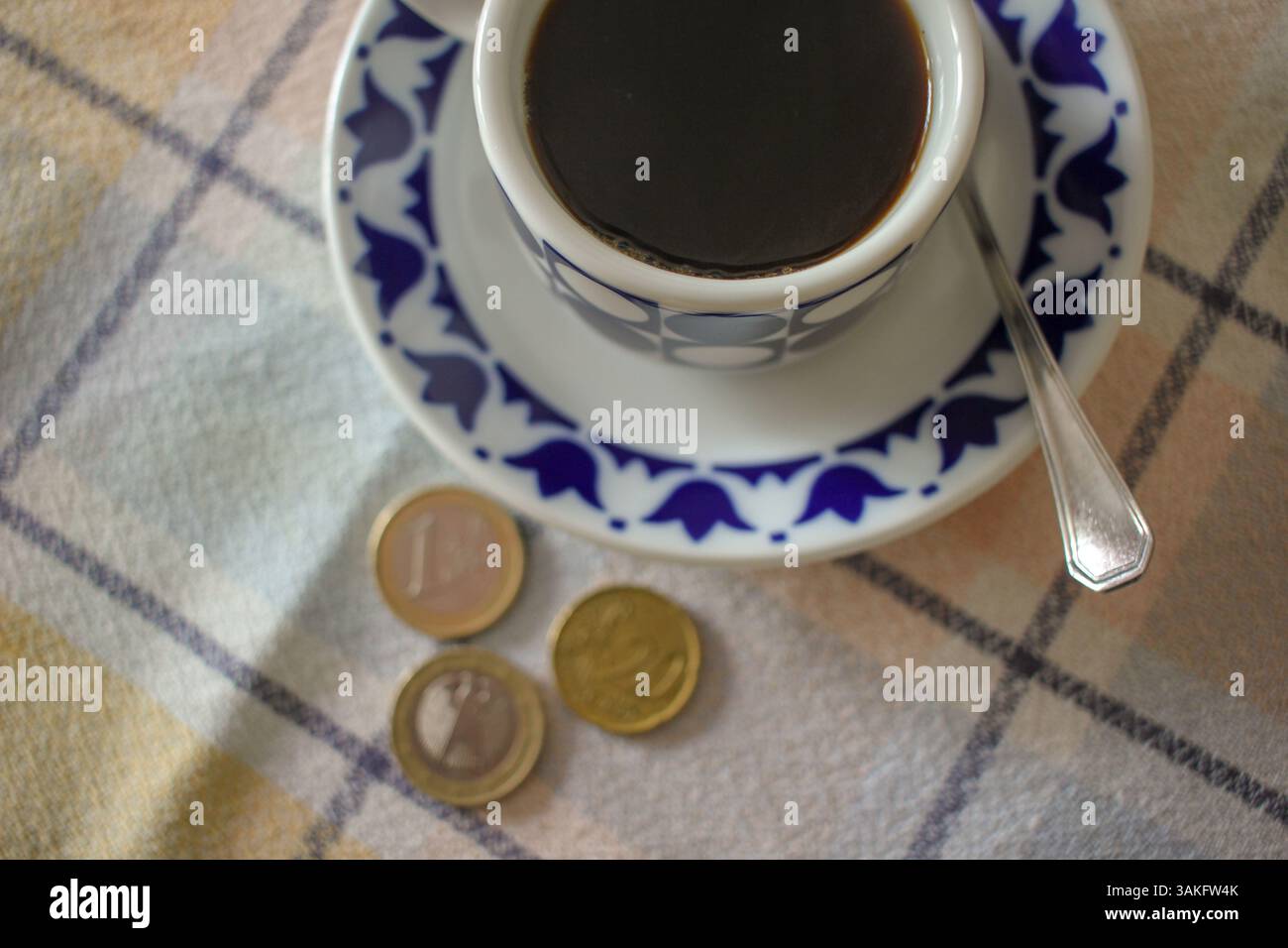 un caffè nero e delle monete. Il prezzo del caffè aumenta Foto Stock