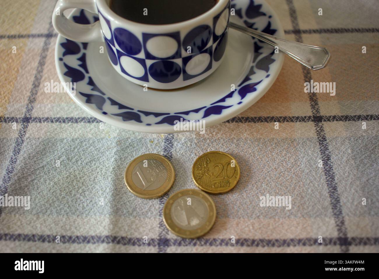 monete in euro e un caffè nero sul tavolo. Aumento del prezzo del caffè Foto Stock