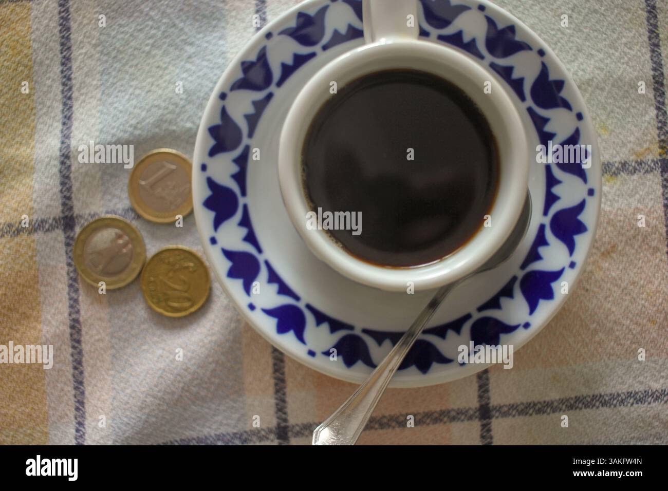 monete in euro e un caffè nero. concetto, il prezzo costoso del caffè a causa dell'inflazione Foto Stock