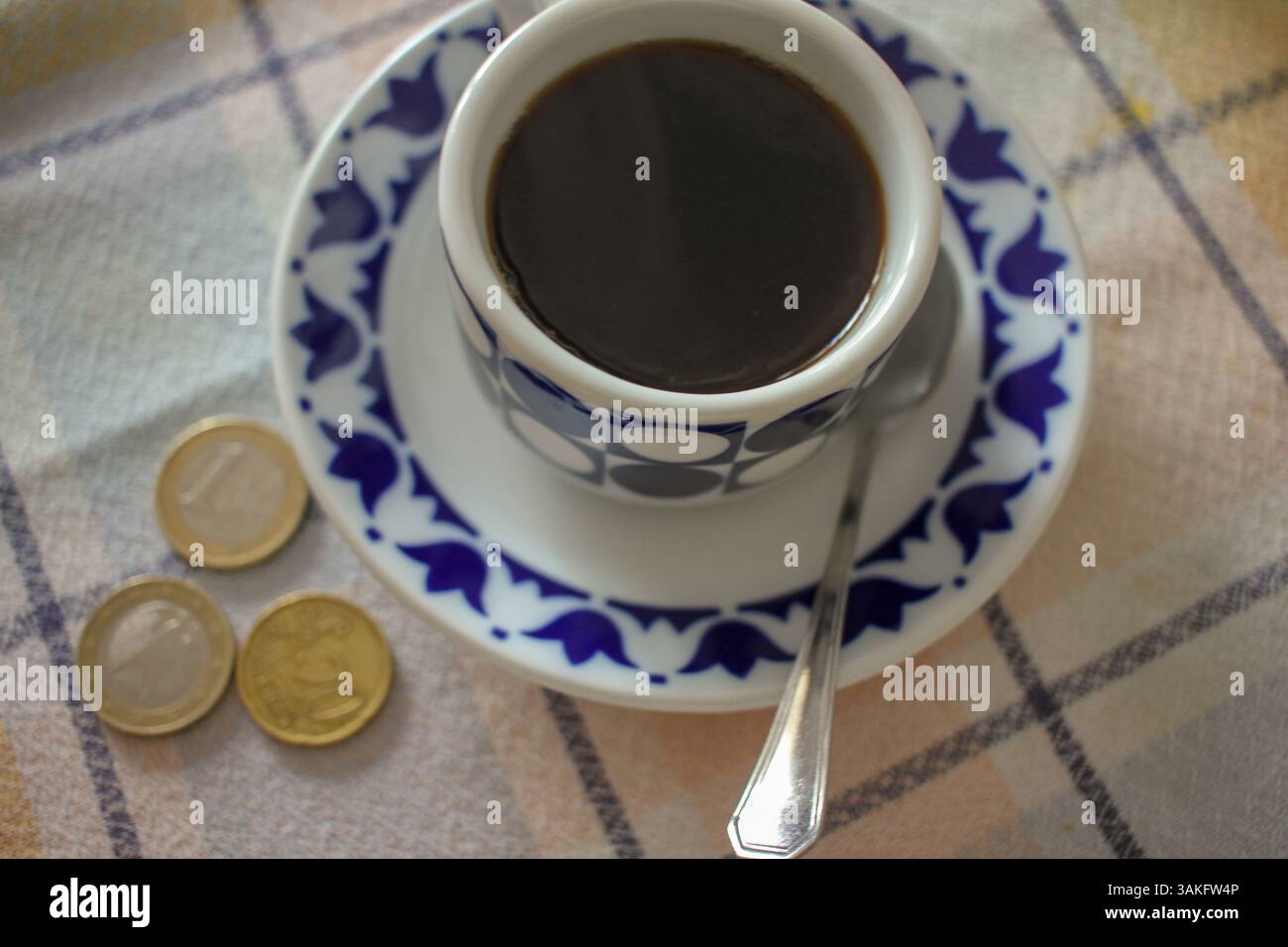 caffè nero e monete sul tavolo. L'alto prezzo del caffè Foto Stock