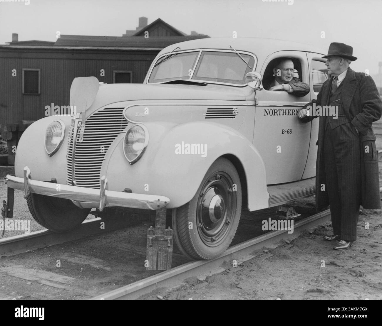 T. M. Flynn, sovrintendente di divisione della Northern Pacific Railway, è al posto di guida di un'auto appositamente attrezzata progettata per viaggiare sui binari del treno. C. C. Price resta in piedi, monitorando gli attraversamenti ferroviari. L'immagine mette in evidenza il veicolo unico utilizzato per le ispezioni dei binari e la sorveglianza della sicurezza ferroviaria. Foto Stock
