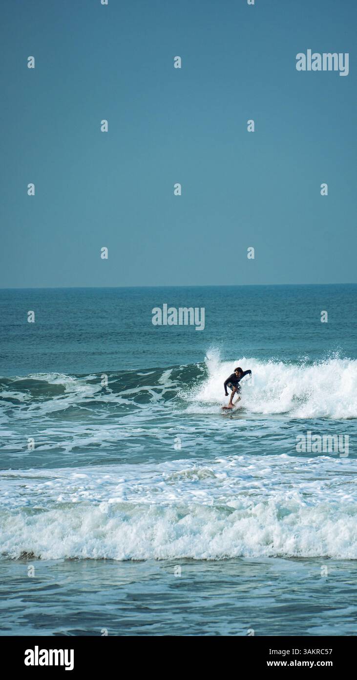 Un uomo che naviga su un'onda pulita a Varkala Beach, Kerala, India. Ripresa con una fotocamera mirrorless Alpha A7 III di Sony Foto Stock