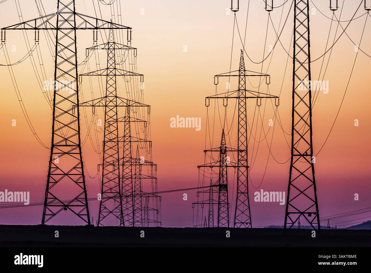 Piloni ad alta tensione, linee elettriche aeree al tramonto. Schwieberdingen, Baden-Wuerttemberg, Germania, Europa Foto Stock