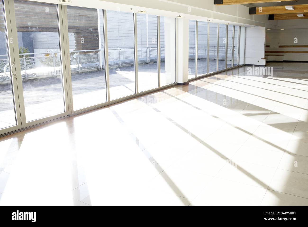 Corridoio vuoto nell'edificio degli uffici con grandi finestre che passano sotto la luce del giorno Foto Stock