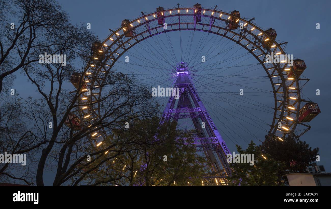 Scatto ad angolo basso della ruota panoramica illuminata a Vienna, Austria. Osservare la città dall'alto Foto Stock