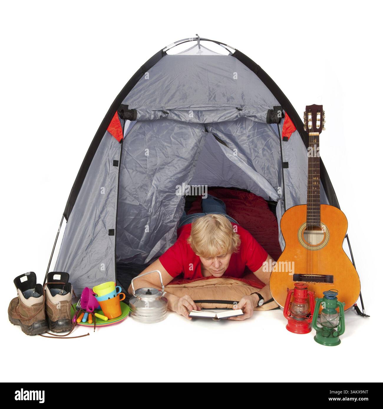 Donna anziana sta leggendo un libro nella tenda del campeggio Foto Stock